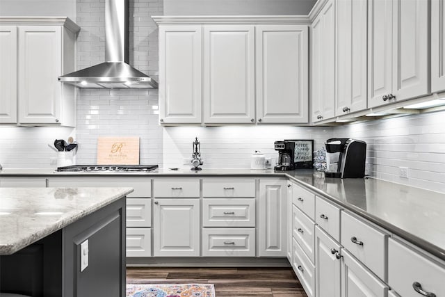 kitchen featuring stainless steel gas cooktop, wall chimney range hood, and white cabinetry