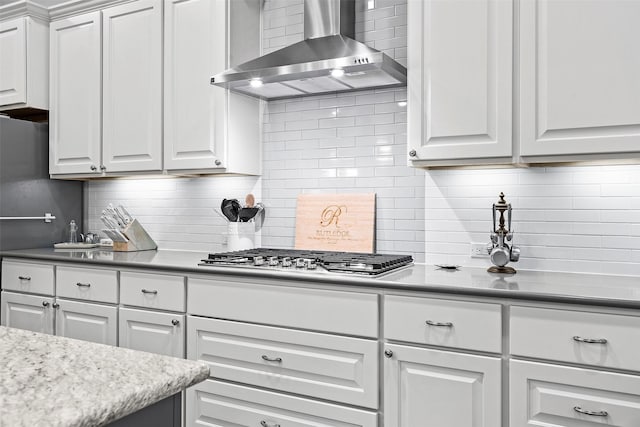 kitchen with white cabinets, wall chimney range hood, and backsplash