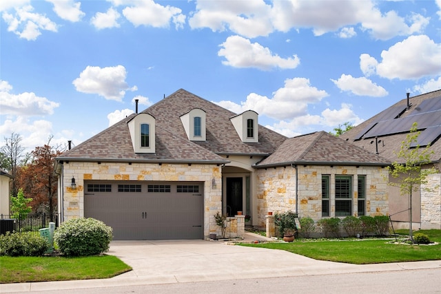 french provincial home featuring a front yard and a garage