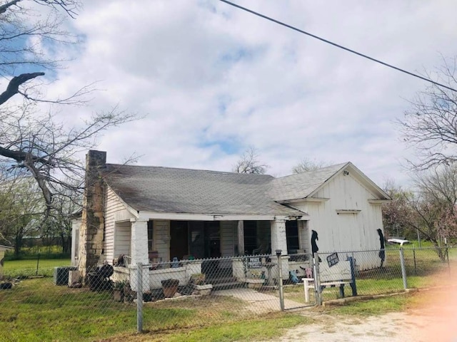 rear view of property with a lawn, central AC, and a porch