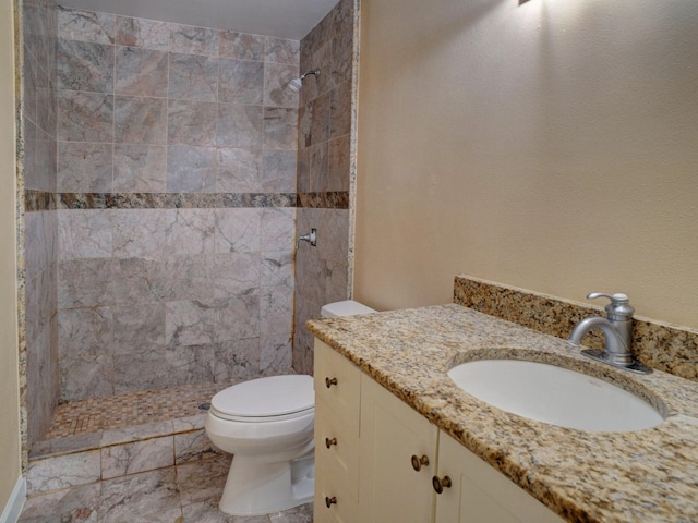 bathroom featuring toilet, tile floors, vanity, and a tile shower