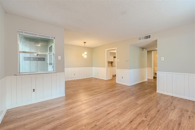 spare room featuring a textured ceiling and light hardwood / wood-style flooring