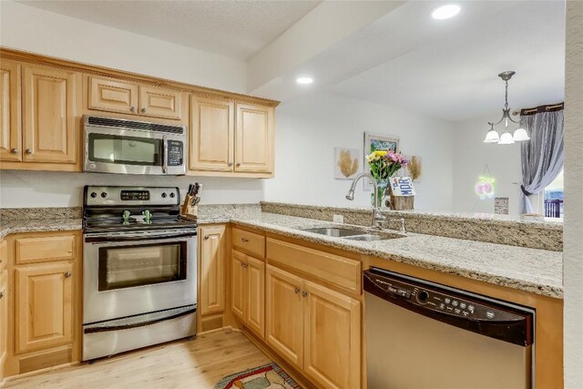 kitchen with sink, light hardwood / wood-style flooring, stainless steel appliances, light stone countertops, and a chandelier