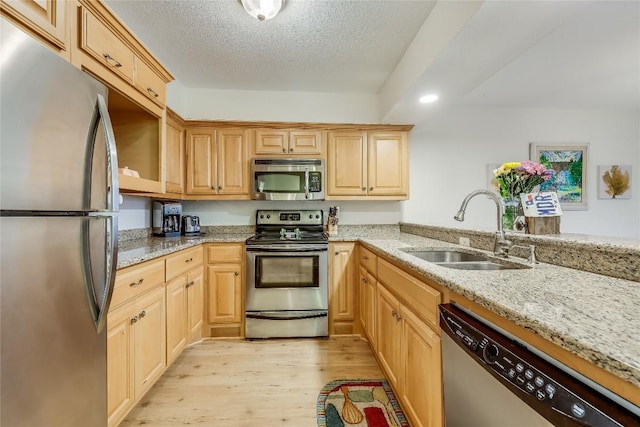 kitchen featuring light stone counters, sink, light hardwood / wood-style flooring, and stainless steel appliances