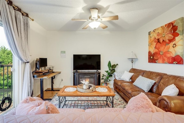 living room featuring ceiling fan, hardwood / wood-style flooring, and a textured ceiling