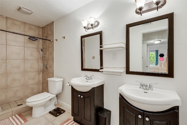 bathroom featuring vanity, tile patterned floors, toilet, and tiled shower