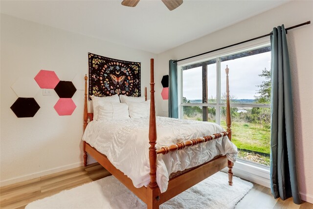 bedroom with ceiling fan, multiple windows, and light wood-type flooring