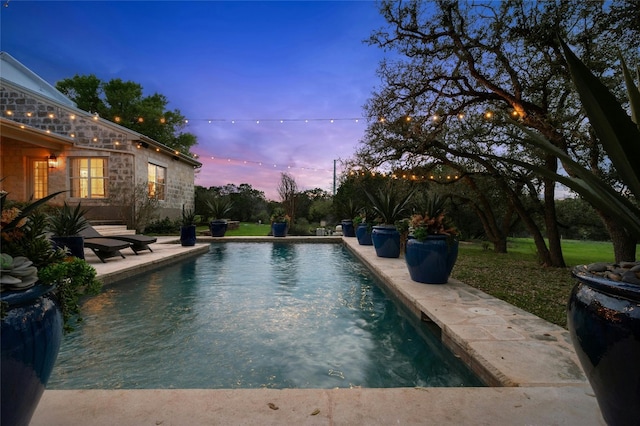 pool at dusk featuring a patio area