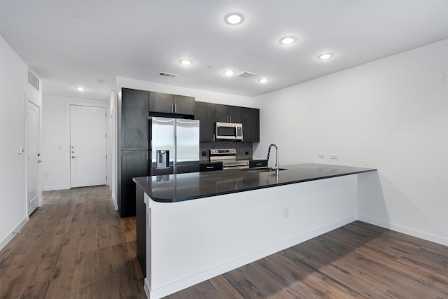 kitchen featuring kitchen peninsula, dark hardwood / wood-style flooring, appliances with stainless steel finishes, and sink