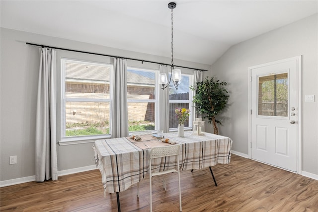 dining area featuring a notable chandelier, lofted ceiling, plenty of natural light, and wood-type flooring