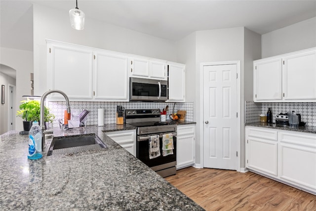 kitchen with white cabinets, appliances with stainless steel finishes, backsplash, and light hardwood / wood-style flooring