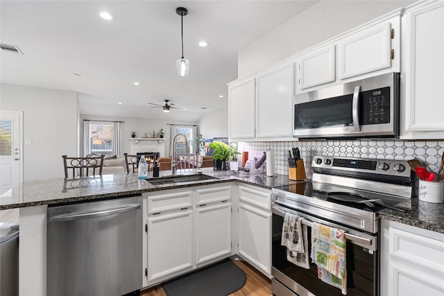 kitchen featuring stainless steel appliances, ceiling fan, dark stone countertops, and sink