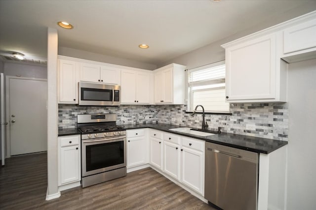 kitchen with dark wood-type flooring, appliances with stainless steel finishes, white cabinets, backsplash, and sink