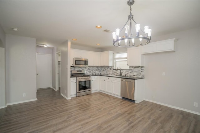 kitchen featuring white cabinets, appliances with stainless steel finishes, hardwood / wood-style floors, and pendant lighting