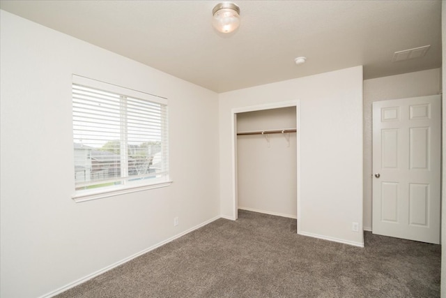 unfurnished bedroom with a closet and dark carpet