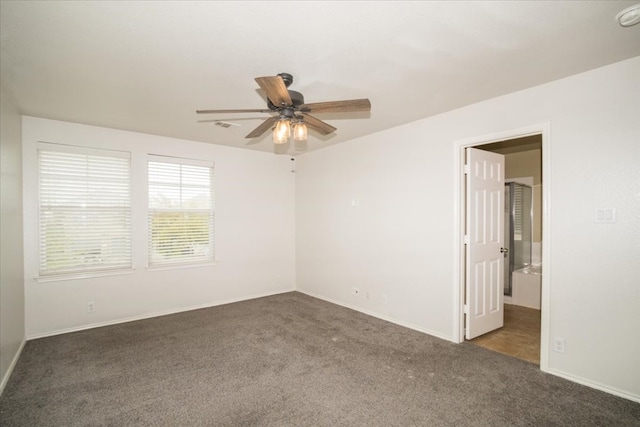 spare room featuring dark carpet and ceiling fan