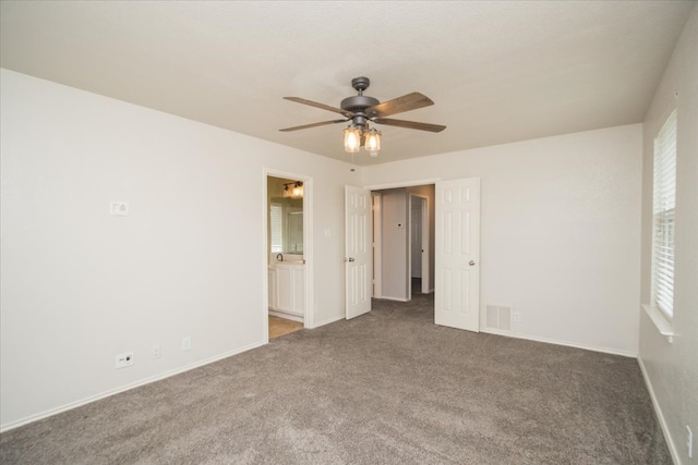 unfurnished room with ceiling fan and dark colored carpet