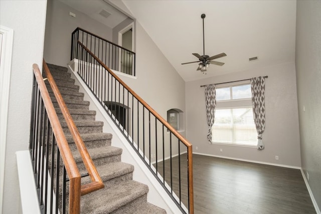 staircase featuring high vaulted ceiling, ceiling fan, and dark hardwood / wood-style floors