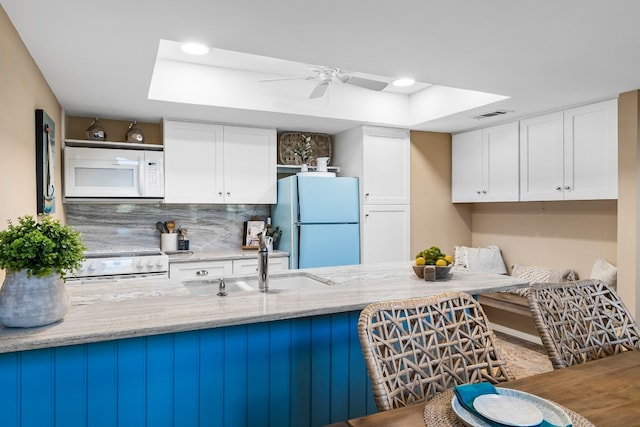 kitchen featuring white cabinets, tasteful backsplash, light stone counters, and white appliances