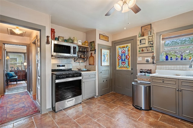 kitchen with a healthy amount of sunlight, gray cabinets, tasteful backsplash, and stainless steel appliances