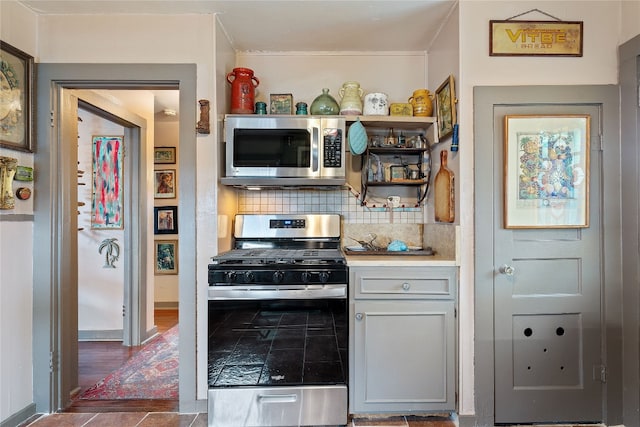 kitchen with backsplash, dark tile flooring, and stainless steel appliances