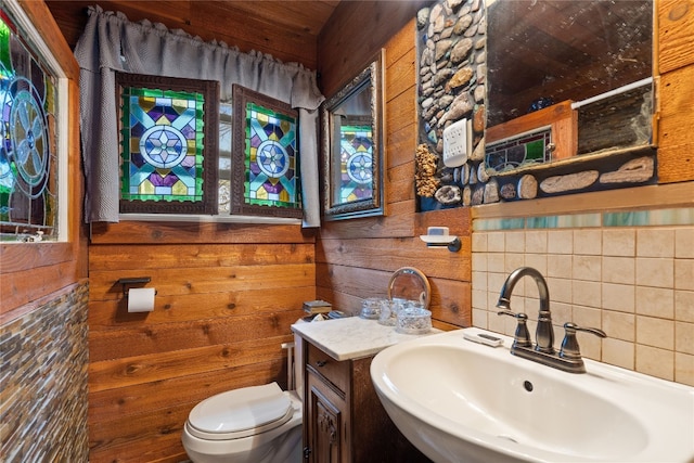 bathroom with backsplash, large vanity, toilet, and wooden walls