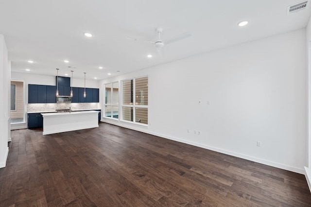 kitchen with pendant lighting, dark wood-type flooring, a center island, blue cabinets, and decorative backsplash