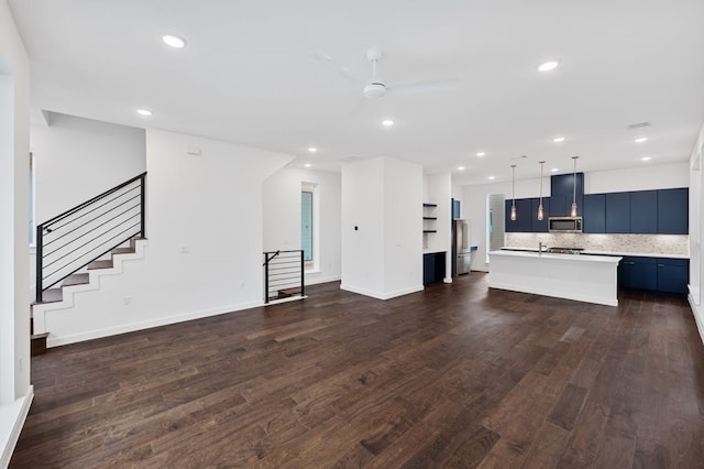 unfurnished living room featuring dark wood-type flooring and ceiling fan