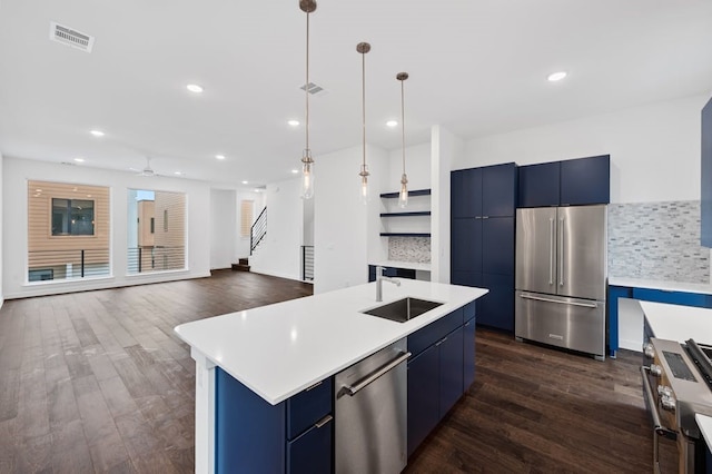 kitchen featuring high end appliances, pendant lighting, sink, and a center island with sink