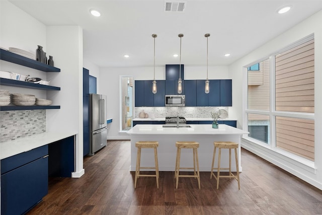 kitchen with pendant lighting, blue cabinets, an island with sink, sink, and stainless steel appliances