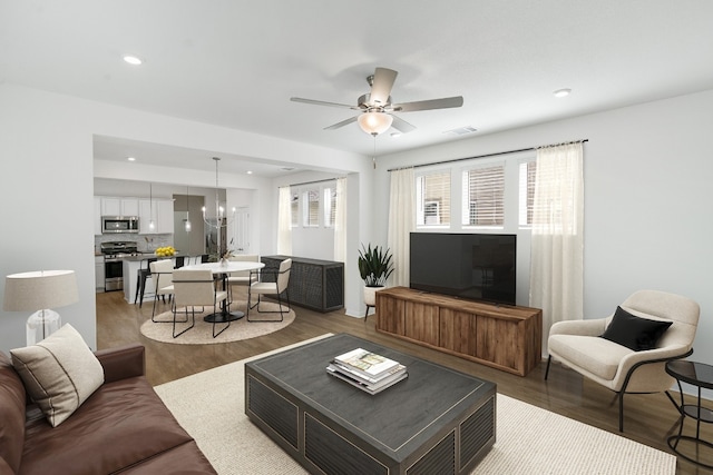 living room featuring hardwood / wood-style floors and ceiling fan with notable chandelier