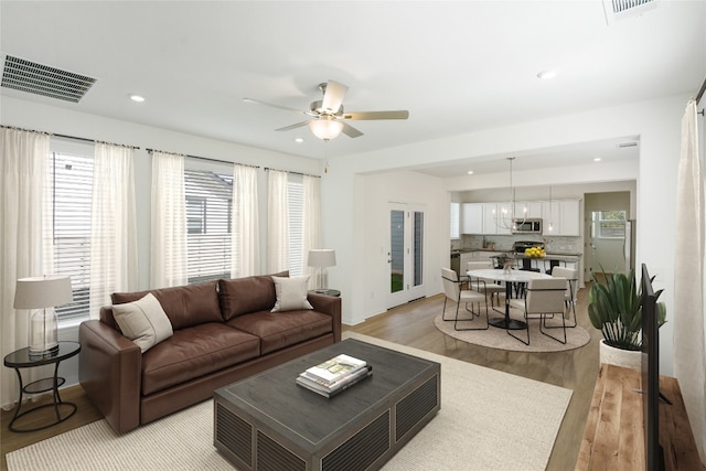 living room with a wealth of natural light, light hardwood / wood-style flooring, and ceiling fan