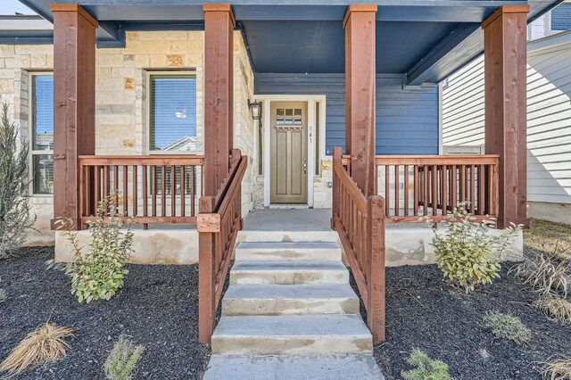 entrance to property featuring covered porch and stone siding