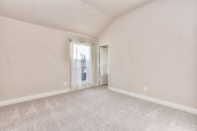 empty room with light colored carpet and vaulted ceiling