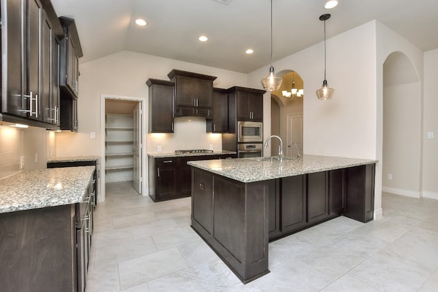 kitchen featuring light tile floors, appliances with stainless steel finishes, decorative light fixtures, and light stone counters