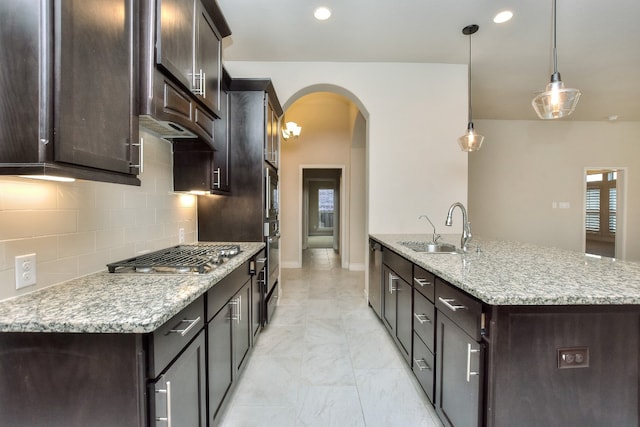 kitchen with sink, hanging light fixtures, light tile flooring, light stone countertops, and tasteful backsplash