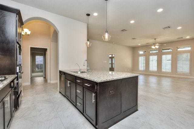 kitchen featuring light tile flooring, a kitchen island with sink, decorative light fixtures, and a wealth of natural light