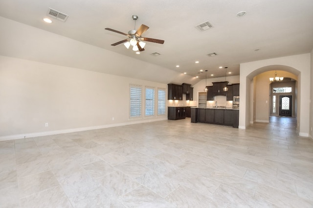 unfurnished living room featuring light tile floors, sink, ceiling fan with notable chandelier, and vaulted ceiling