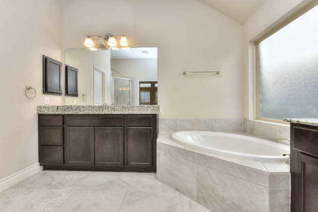 bathroom with tiled tub, tile floors, vanity, and a wealth of natural light