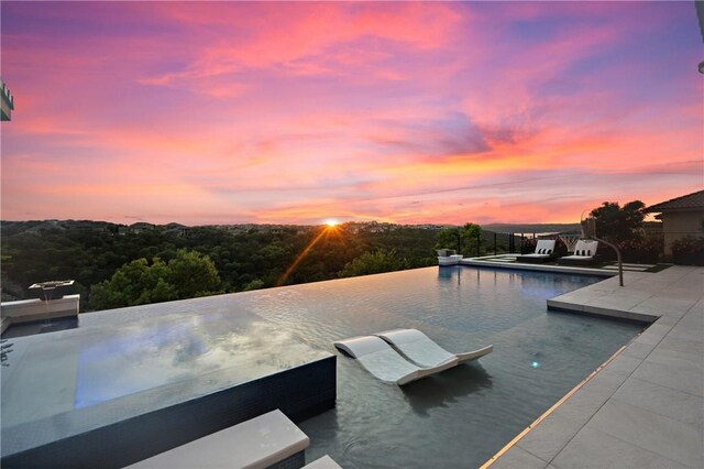 pool at dusk with a patio area