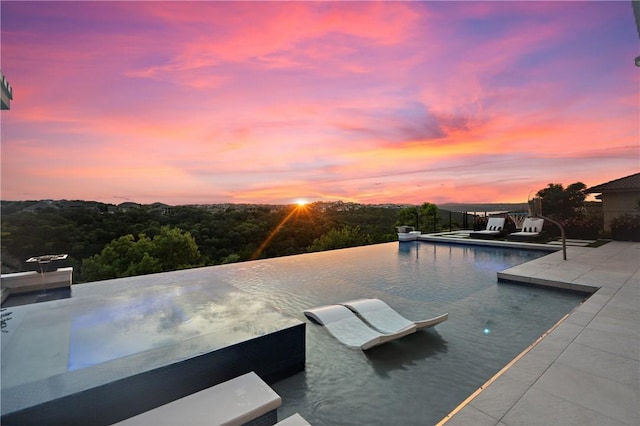 pool at dusk featuring a patio