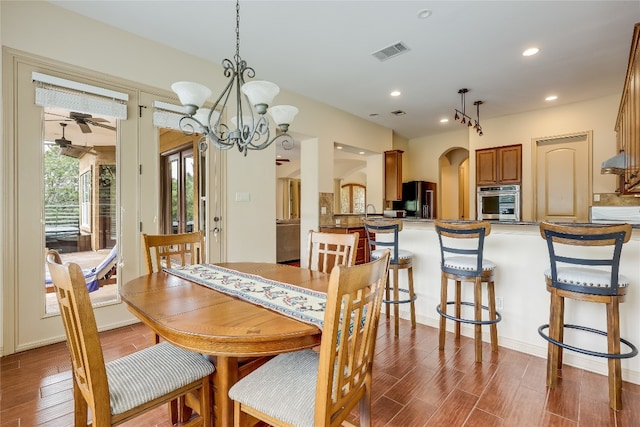 dining area with dark hardwood / wood-style floors and ceiling fan with notable chandelier