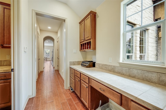 kitchen with lofted ceiling, tile counters, and light hardwood / wood-style floors