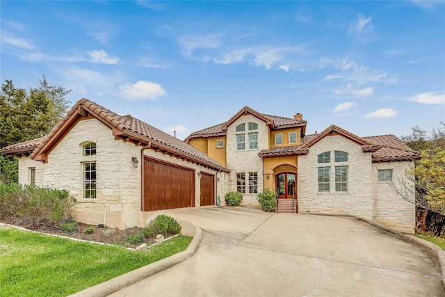 mediterranean / spanish home featuring a front yard and a garage