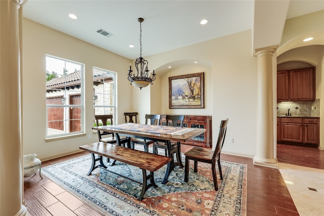 tiled dining room with a notable chandelier and ornate columns