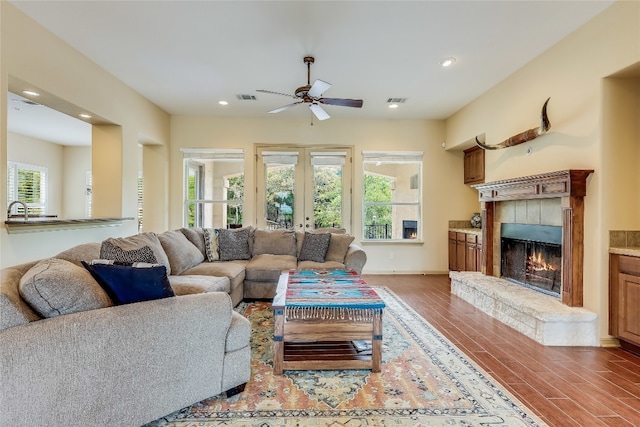 living room featuring dark hardwood / wood-style flooring, a fireplace, ceiling fan, and a wealth of natural light