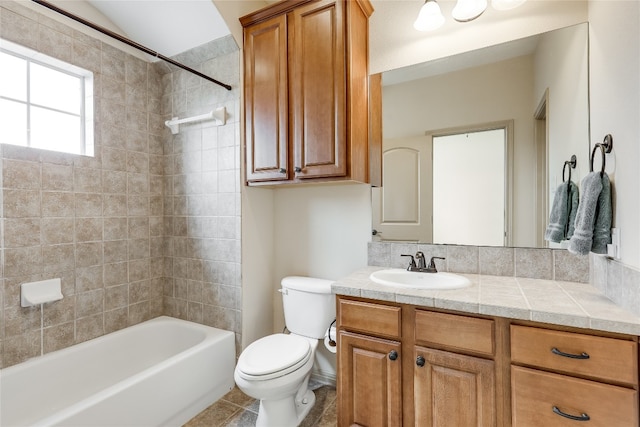 full bathroom with tile flooring, large vanity, toilet, and tiled shower / bath