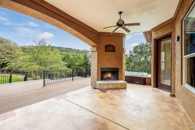 view of terrace with an outdoor stone fireplace and ceiling fan