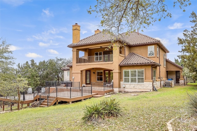 back of property with a deck, a balcony, a yard, and central AC