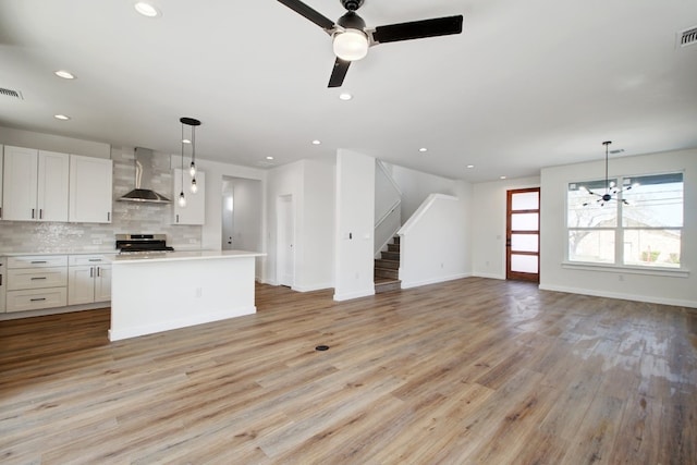 kitchen with range, decorative light fixtures, wall chimney exhaust hood, and light wood-type flooring